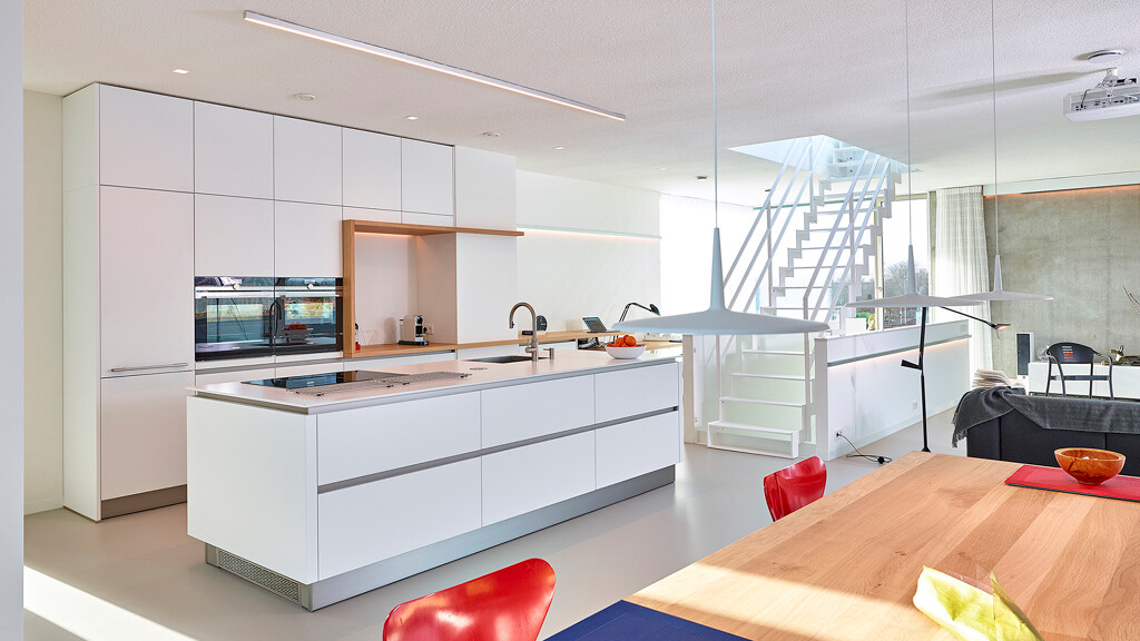 Grifflose Inselküche von Contur in weiße Satinlack mit weiße Komposit Arbeitsplatte und Holzdetails. Ekelhoff-Küchen in Nordhorn.