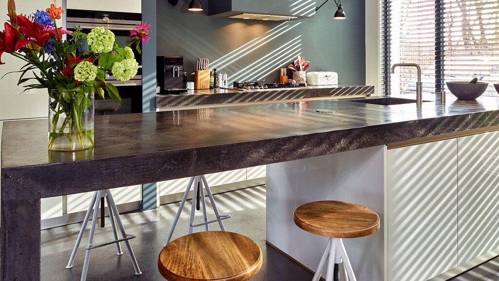 Spülinsel mit Betonarbeitsplatte, Barhockern und bunten Blumen