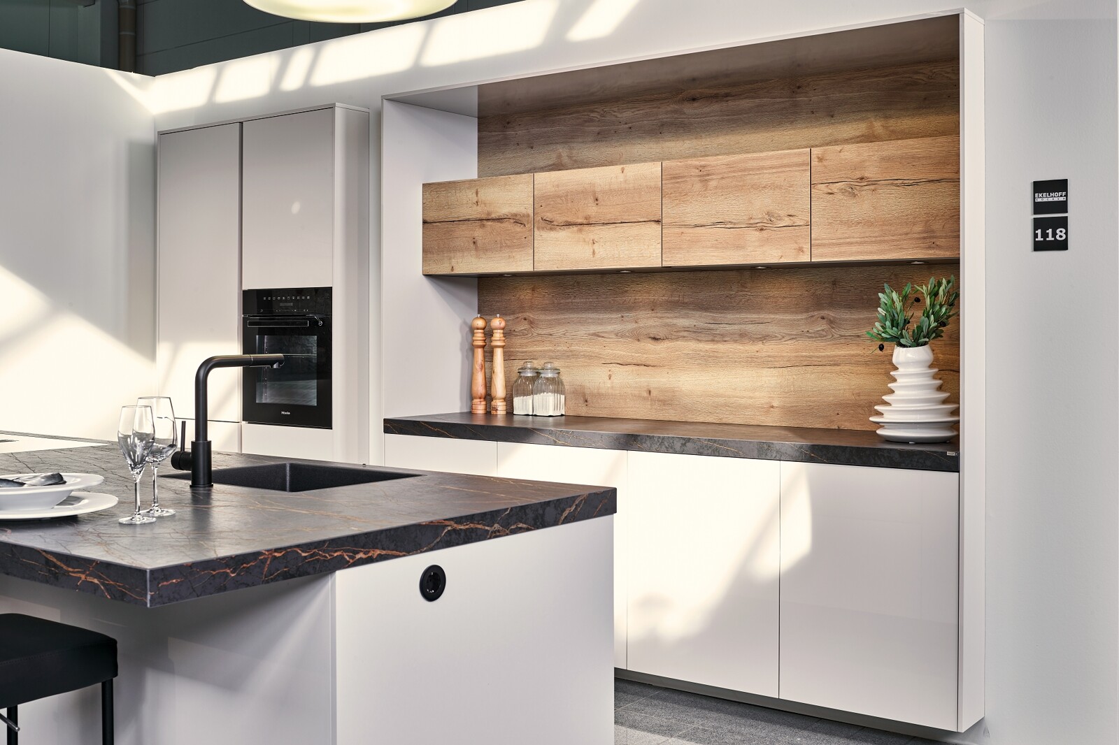Showroomkeuken: eilandkeuken in hoogglans schelpwit van Contur met keramiek Dekton blad en houten achterwand