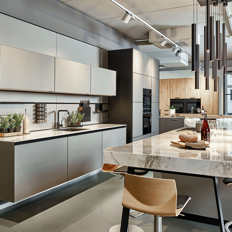 Schöne next125 Küche mit Kücheninsel in Platin Metallic Mattglas. Mit next Cube Rückwand. Zu sehen im Küchenhaus Ekelhoff in Nordhorn.