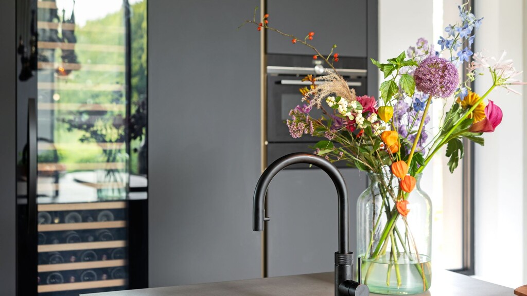 Ontdek deze prachtige SieMatic SLX Pure eilandkeuken in zwart en notenhout met rvs keukenblad en Quooker. Gerealiseerd in Laren door Ekelhoff Keukens, Nordhorn.