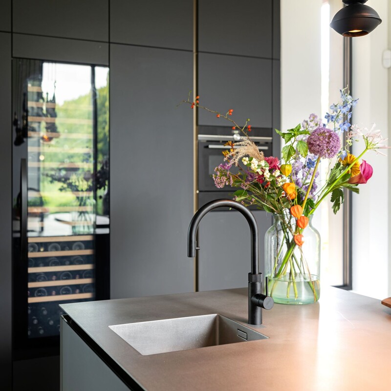 Ontdek deze prachtige SieMatic SLX Pure eilandkeuken in zwart en notenhout met rvs keukenblad en Quooker. Gerealiseerd in Laren door Ekelhoff Keukens, Nordhorn.