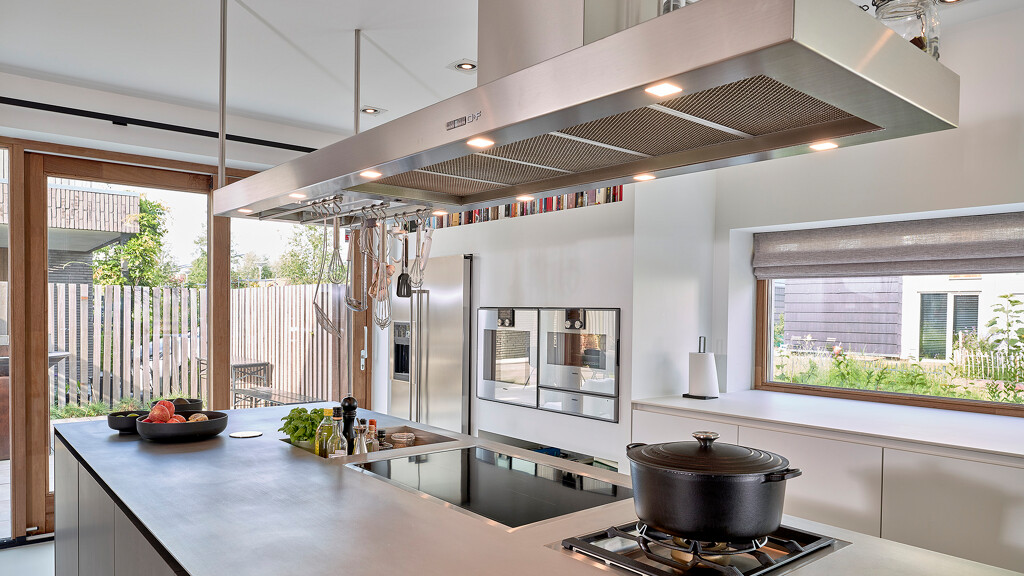 Industrieel keukeneiland met  grote afzuigkap en rvs keukenblad