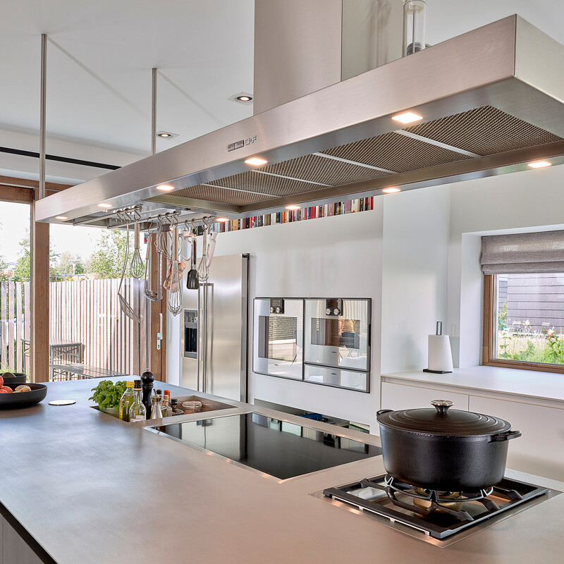 Industrielle Kücheninsel mit großer Dunstabzugshaube und Edelstahl Arbeitsplatte.