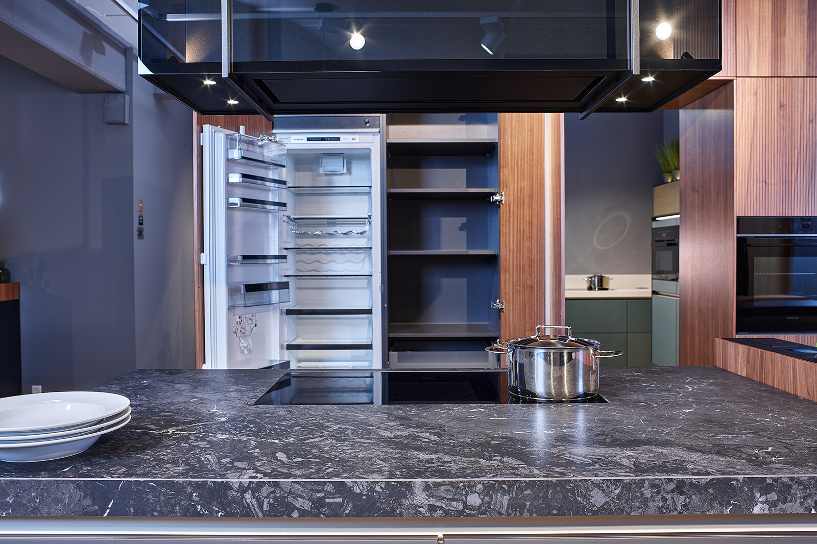 Showroomkeuken: next125 design eilandkeuken met ribbelfronten in notenhout en matglas met Siemens apparatuur