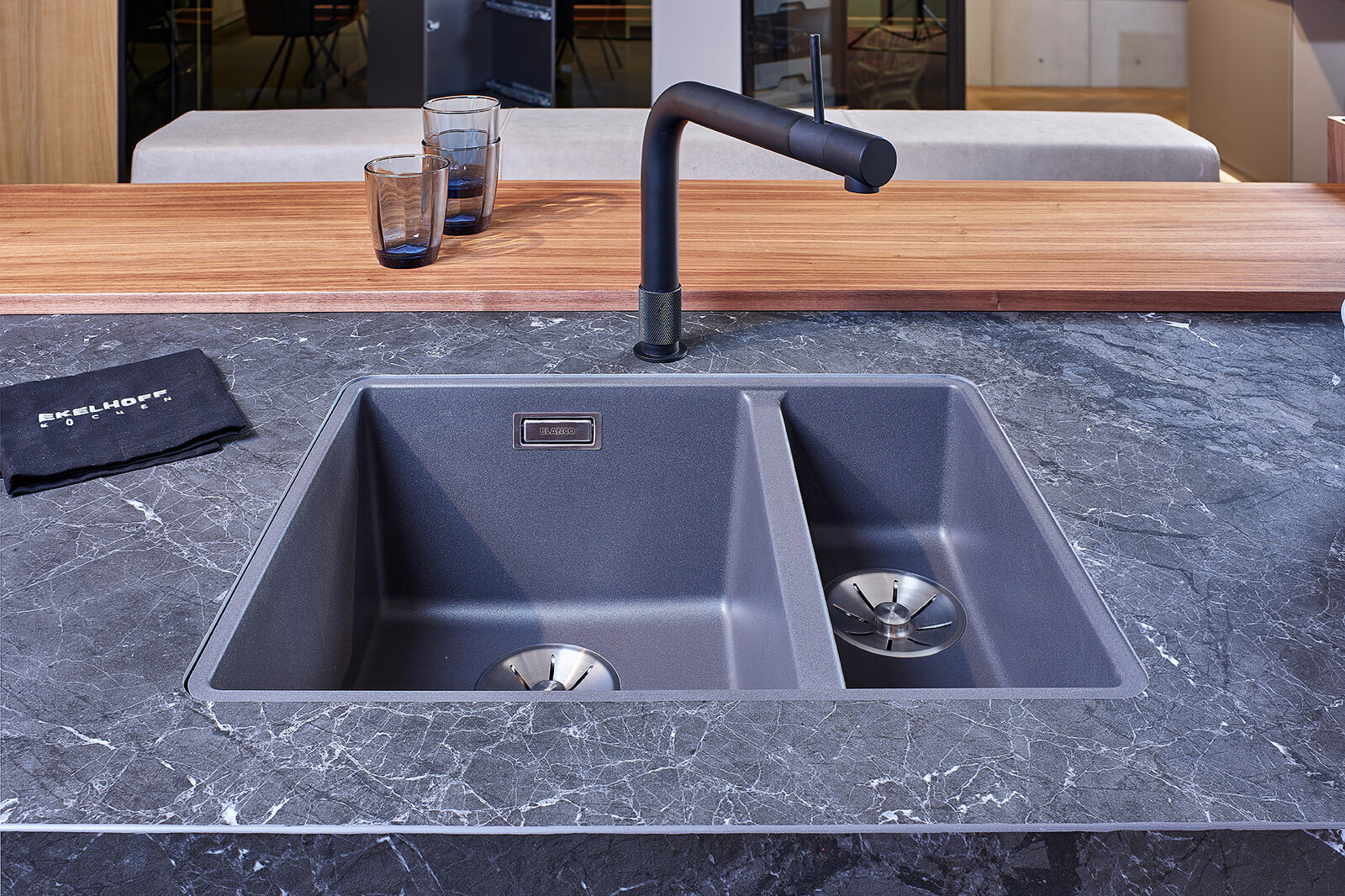 Showroomkeuken: next125 design eilandkeuken met ribbelfronten in notenhout en matglas. Dubbele silgranit spoelbak