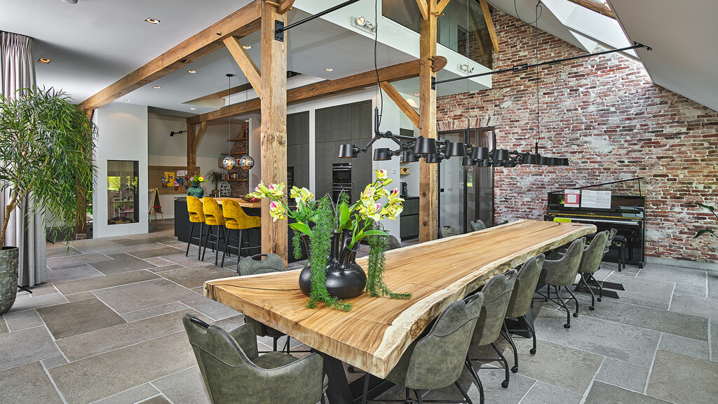 Wohnküche von next125 in Eiche und schwarzem Mattglas. Die Bar aus Holz hat eine Natur- oder Baumkante, ebenso wie der lange Tisch im Vordergrund. Entdecken Sie Ekelhoff Küchen in Nordhorn.