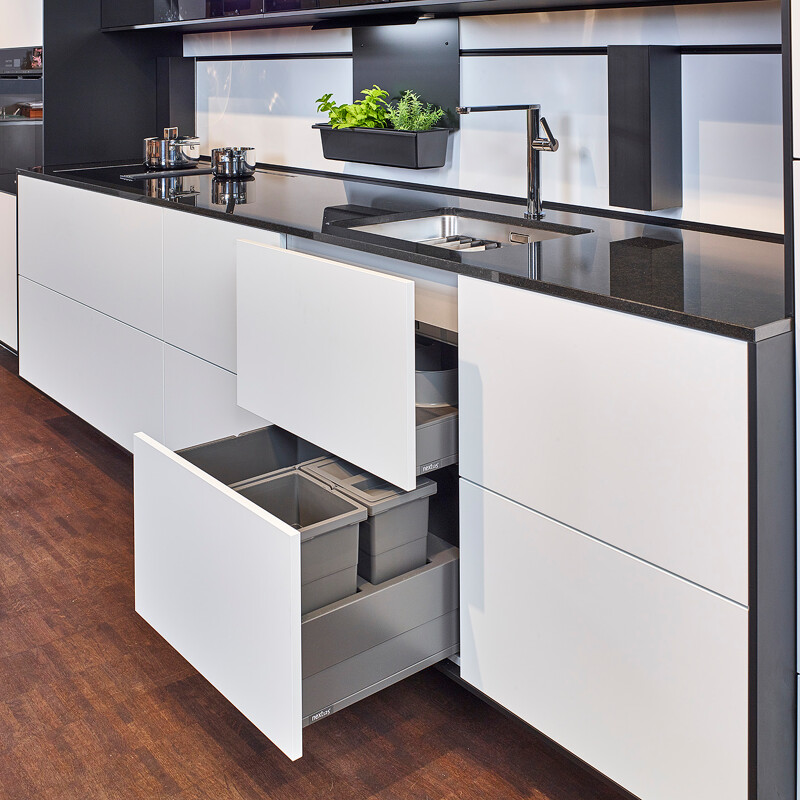 Küchennische mit Koch- und Spülbereich und geöffneten Schubladen unter der Spüle für das Abfallsystem