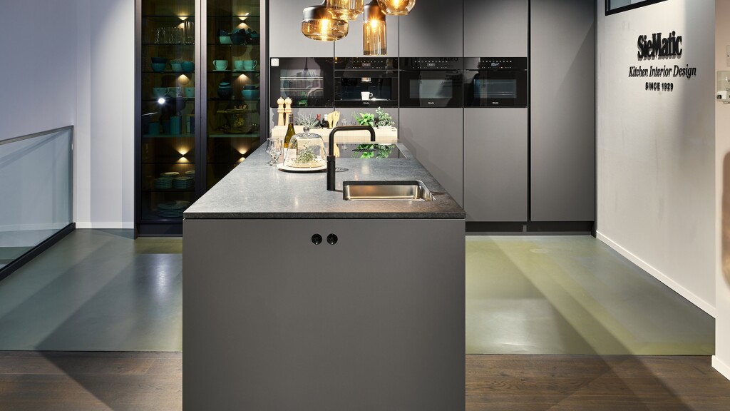 Siematic-keuken Urban S2, SLS in mat grafietgrijs. Te zien in de keukenshowroom van Ekelhoff, Nordhorn. Met vitrinekasten en granieten aanrechtblad.