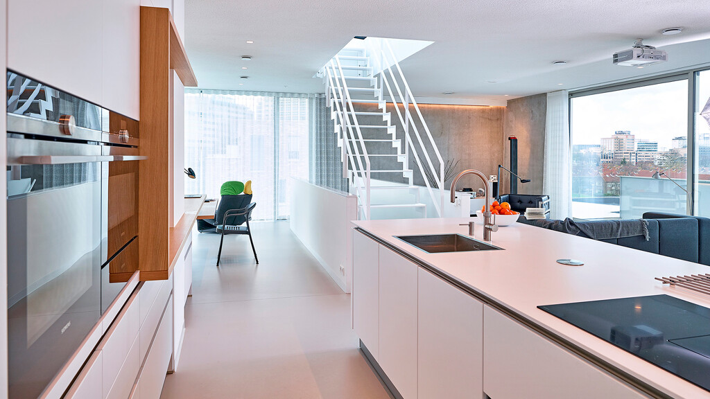 Grifflose Inselküche von Contur in weiße Satinlack mit weiße Komposit Arbeitsplatte und Holzdetails. Ekelhoff-Küchen in Nordhorn.