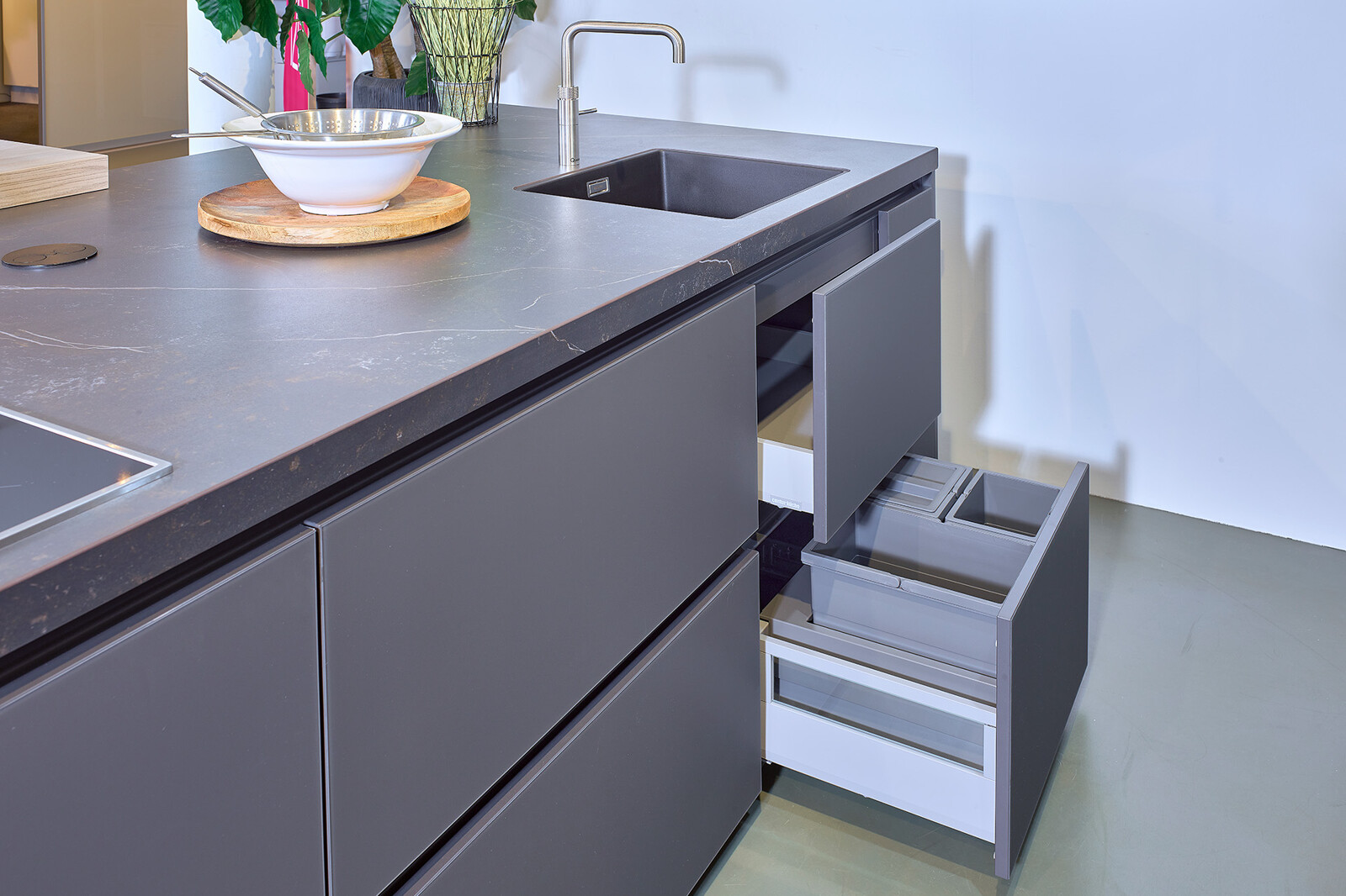 Showroomkeuken: zwarte eilandkeuken met houten kastenwand van Contur met afvalsysteem