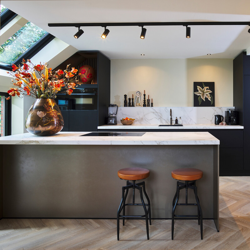 Zwarte Ballerina keuken met matte smartglas fronten en  keramiek werkblad van Dekton. Woonkeuken met kookeiland van vazen schilderes Margo Houwing