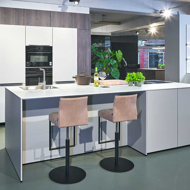 Stijlvolle eilandkeuken in kiezelgrijs en donker eiken (im.). Het werkblad is van keramiek in marmerlook, aan het eiland is plaats voor 2 barkrukken. incl kookplaat met afzuiging van Airo Design