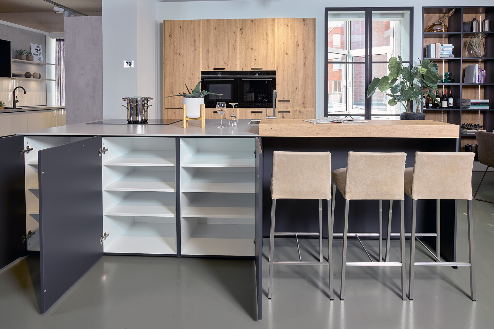 Showroomkeuken: Eilandkeuken met bar in lavazwart en eiken met wit composiet keukenblad en veel kastruimte