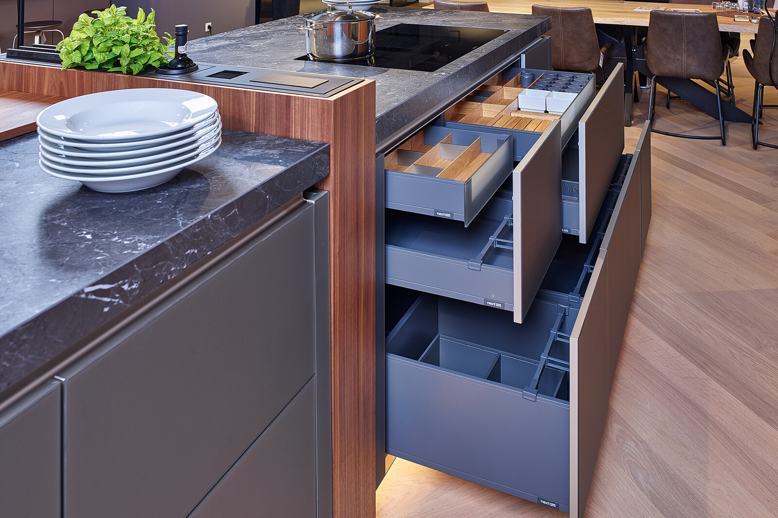 Showroomkeuken: next125 design eilandkeuken met ribbelfronten in notenhout en matglas met veel lades en luxe ladeinrichting