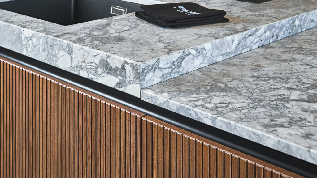 Detaill van next125 designkeuken met notenhouten rillenfronten en granietsoort Superwhite. Ekelhoff Keukens in Duitsland