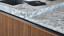 Detaill van next125 designkeuken met notenhouten rillenfronten en granietsoort Superwhite. Ekelhoff Keukens in Duitsland