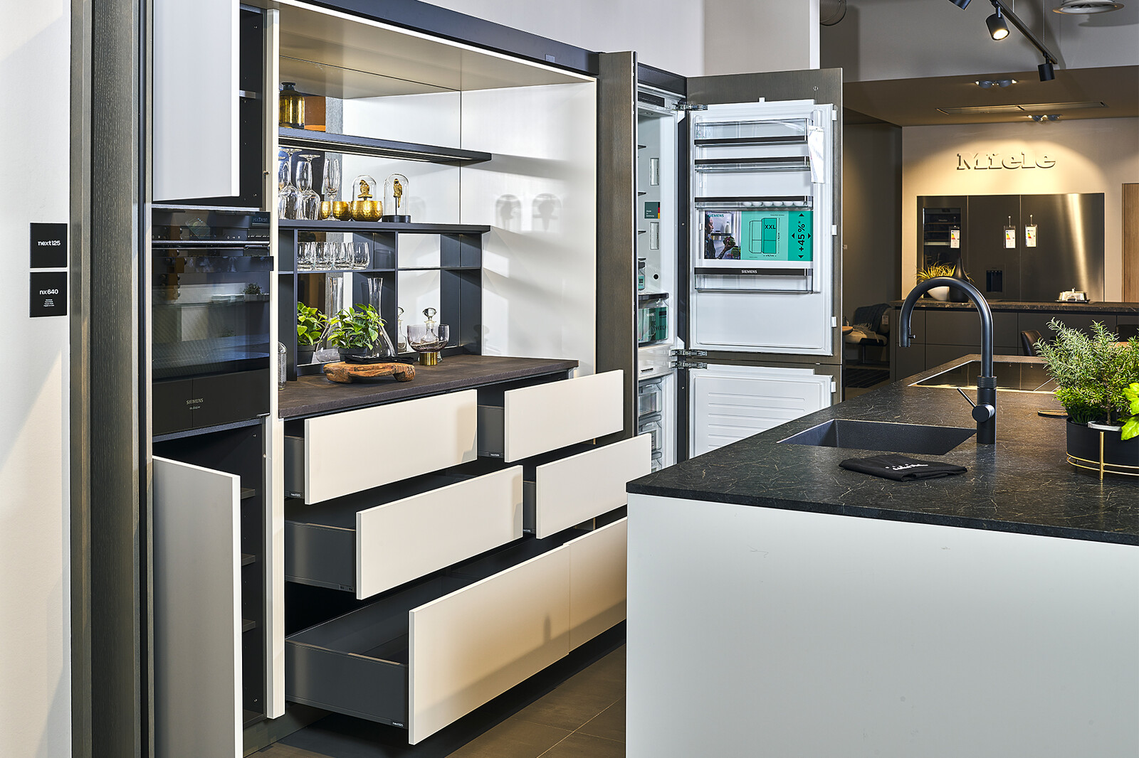 next125 design showroomkeuken met pocketdeuren, keukeneiland en Black Ice graniet