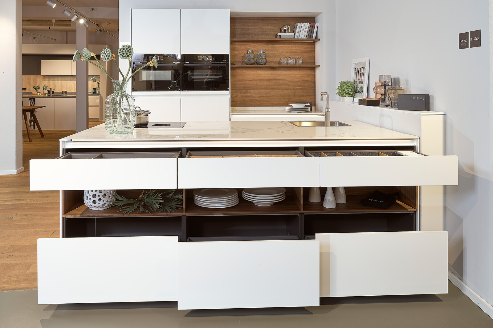 Showroomkeuken next125 - Witte eilandkeuken in fenix met notenhout en veel brede lades