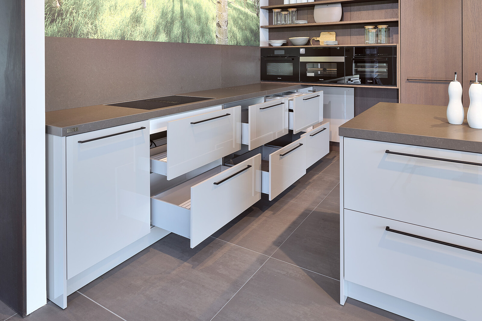 Showroomkeuken: SieMatic designkeuken in L-vorm met keukeneiland in lichtgrijs en eiken  met veel brede lades