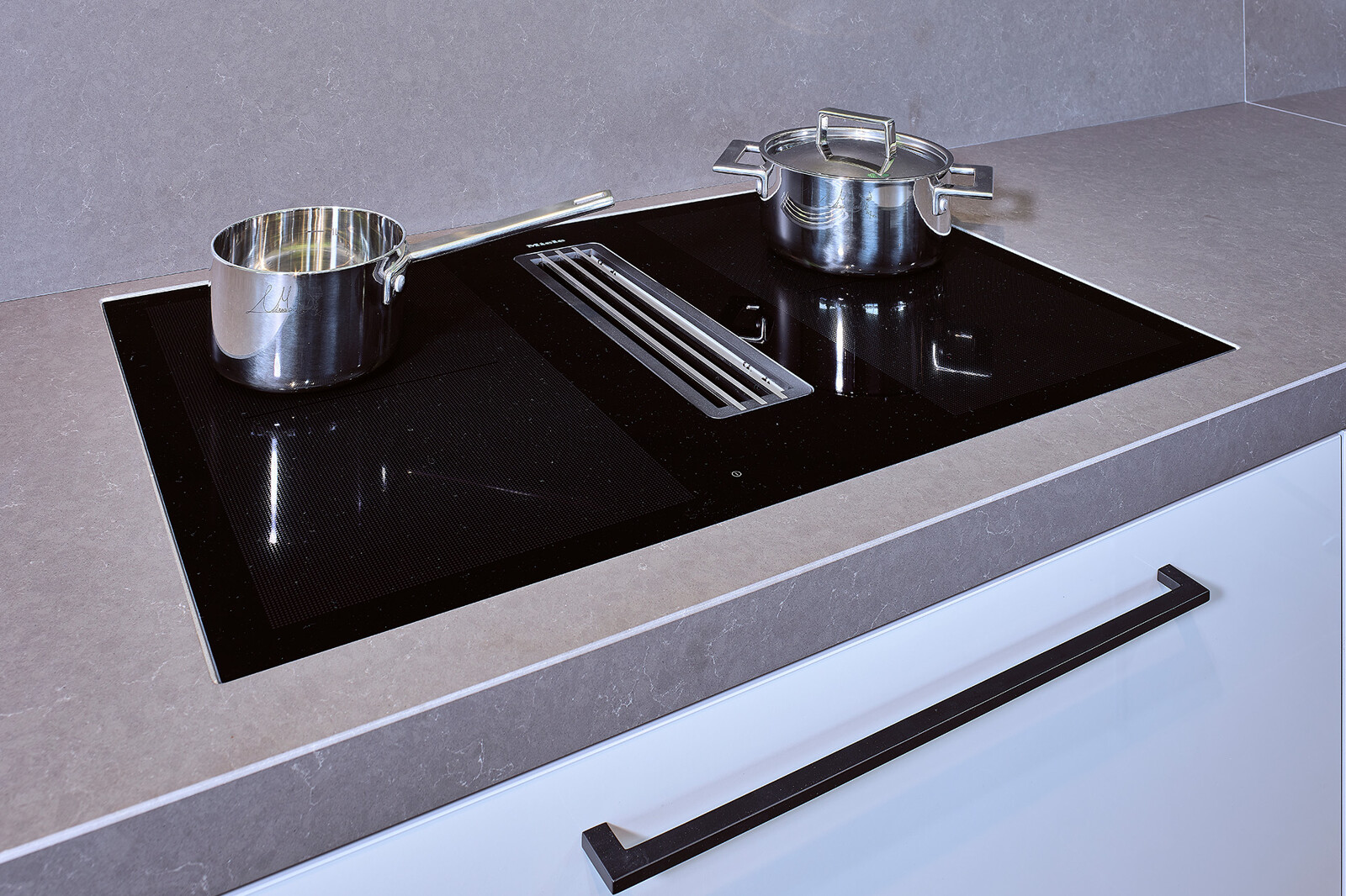Showroomkeuken: SieMatic designkeuken in L-vorm met spoeleiland en aanrecht met kookplaat van Miele