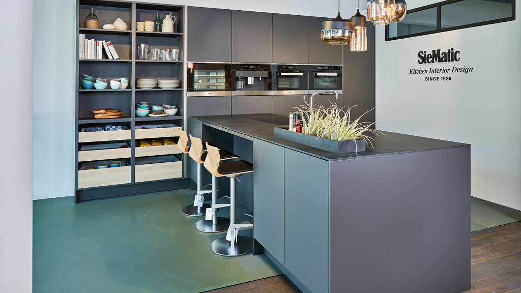 SieMatic Wohnküche in Graphitgrau matt mit Insellösung, Platz für drei Barhocker, Hochschränken und hohen offenen Schränken