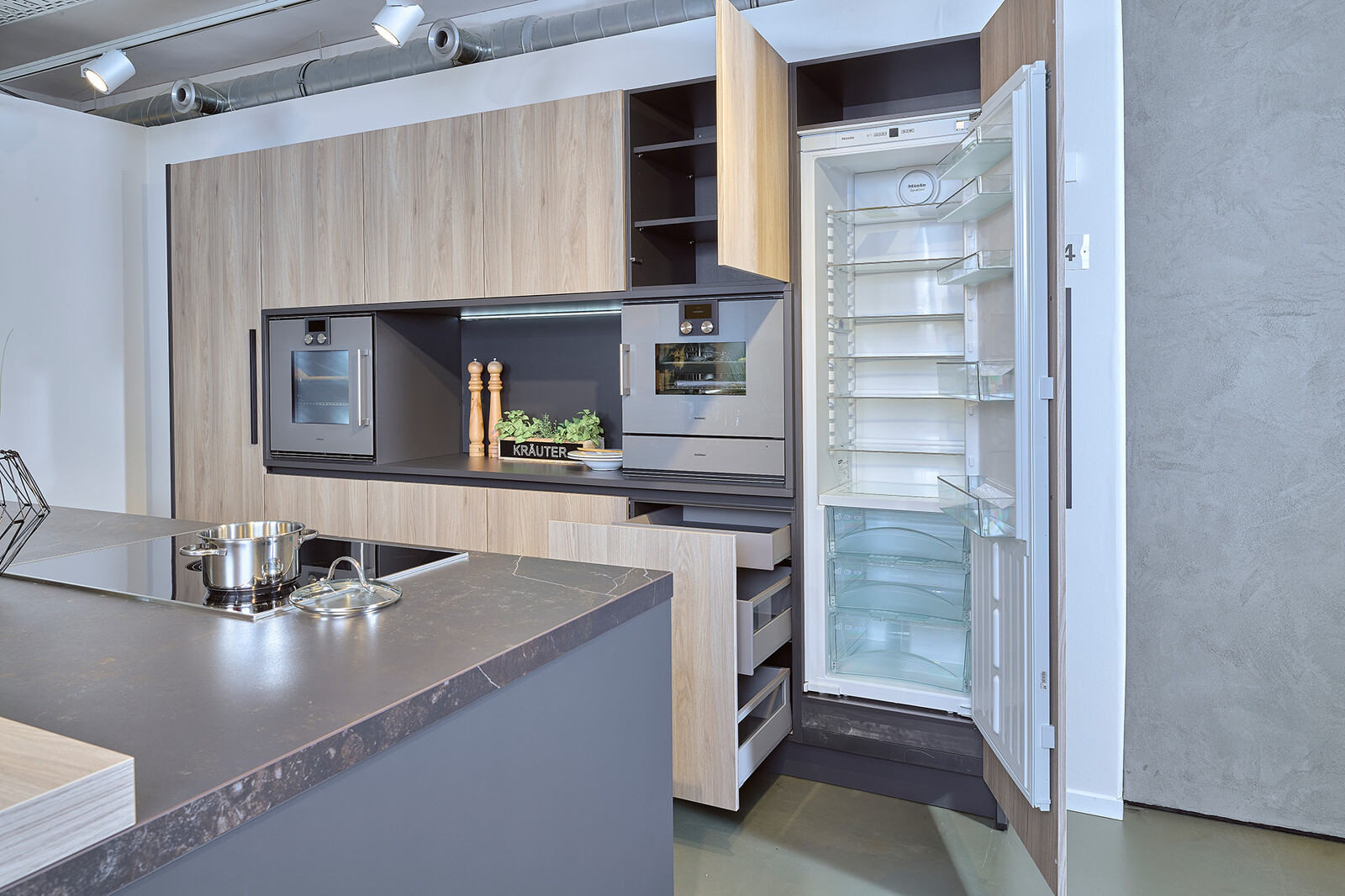 Showroomkeuken: zwarte eilandkeuken met houten kastenwand van Contur met Neff apparatuur