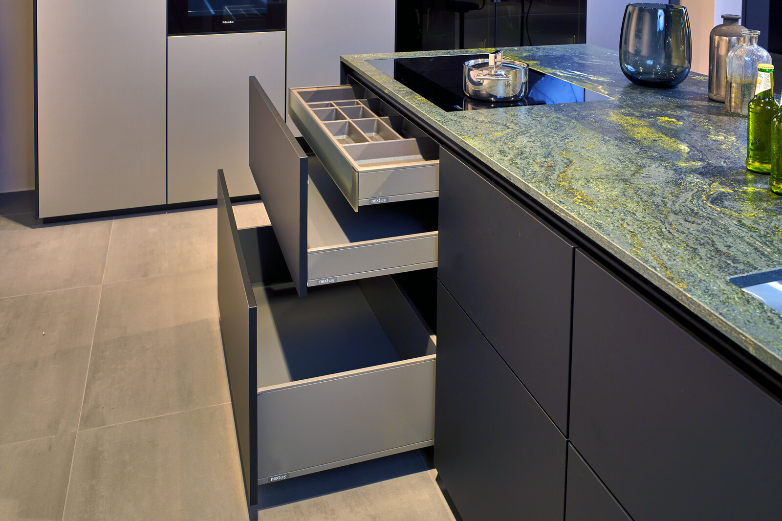 Showroomkeuken: next125 designkeuken in metallic Inox SensiQ met brede lades