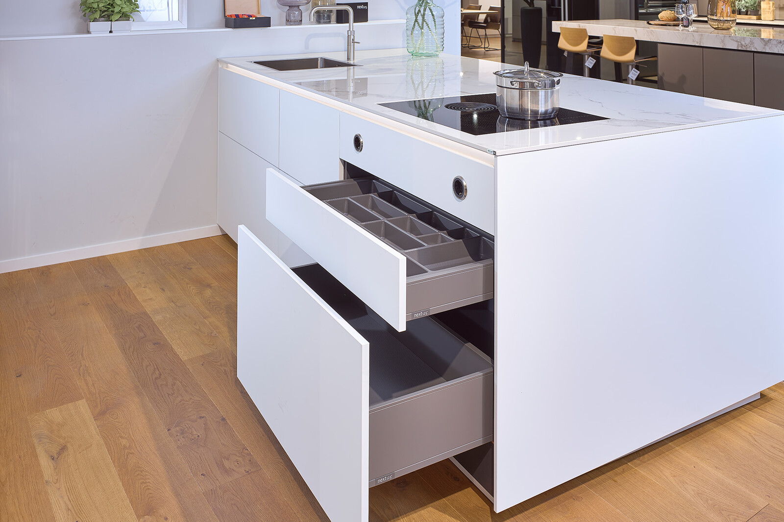 Showroomkeuken next125 - Witte eilandkeuken in fenix en notenhout met praktische lades