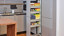 Geopende apothekerskast met voorraden in een grijze hoekkeuken van Schuller keukens uit Duitsland