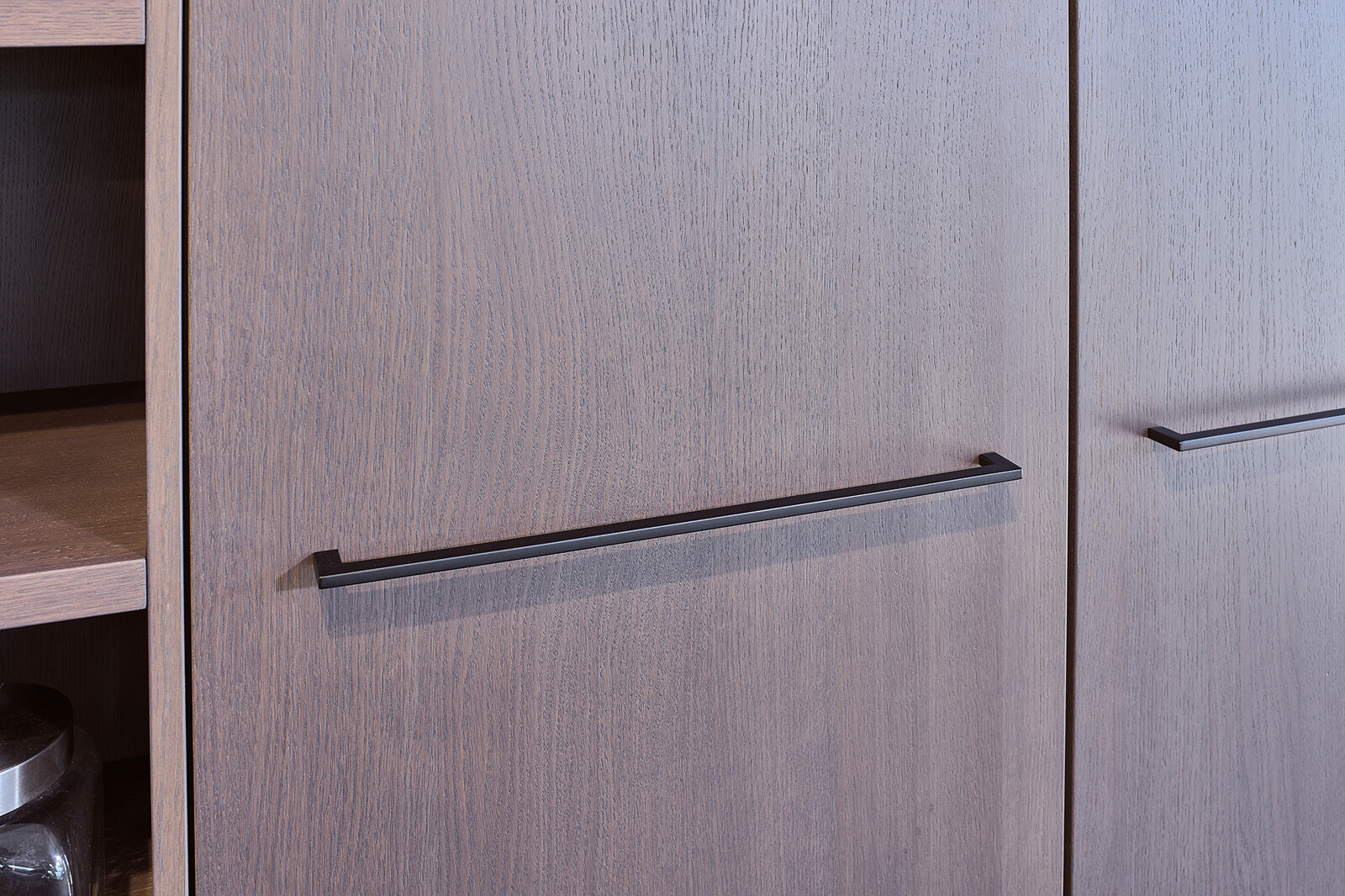 Showroomkeuken: SieMatic designkeuken met lichtgrijs keukeneiland en Hazelbrown eikenfineer kastenwand