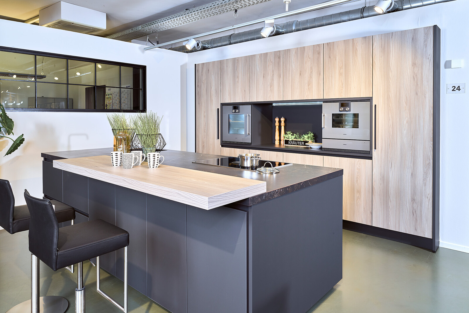 Showroomkeuken: Zwarte eilandkeuken met houten kastenwand en bar en Dekton blad