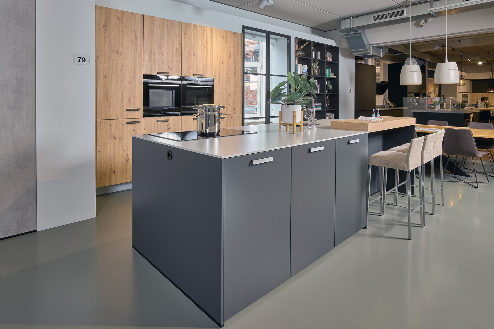Showroomkeuken: Eilandkeuken in matzwart en eiken met wit composiet keukenblad