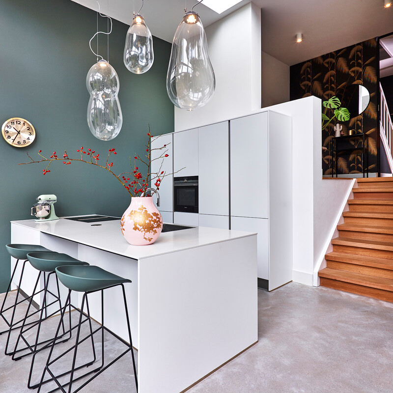 Schlichte grifflose Inselküche in mattweiß mit weißer Arbeitsplatte in Marmoroptik von Ekelhoff Küchen