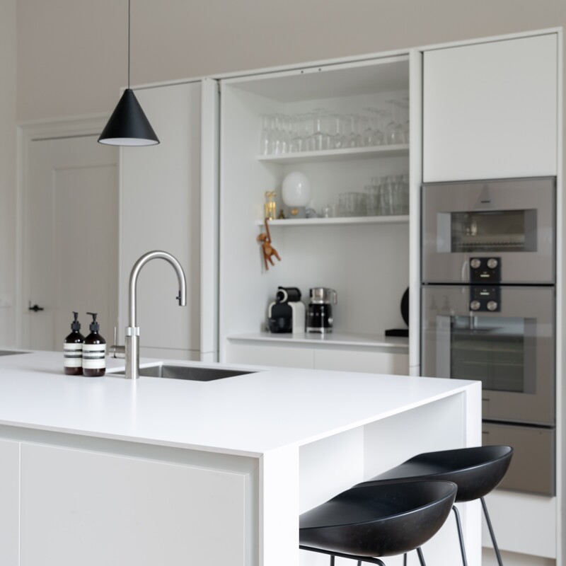 Een witte keuken met nis en pocket deuren. Mies Interieur, Charlotte Kap Fotografie