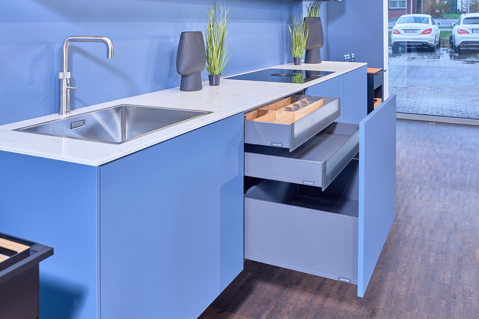 Showroomkeuken: next125 Blauwe designkeuken met wit keukenblad en binnenlades