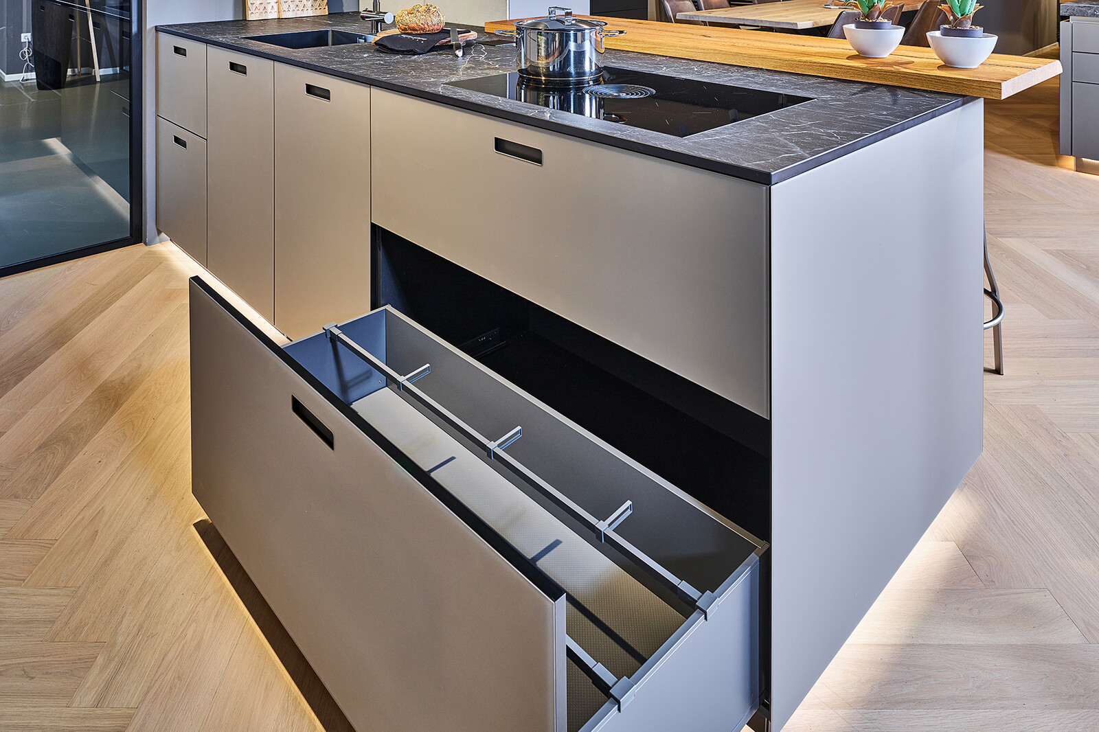 Showroomkeuken: next125 industriële eilandkeuken met keramisch aanrechtblad Somnia houten bar en brede lades