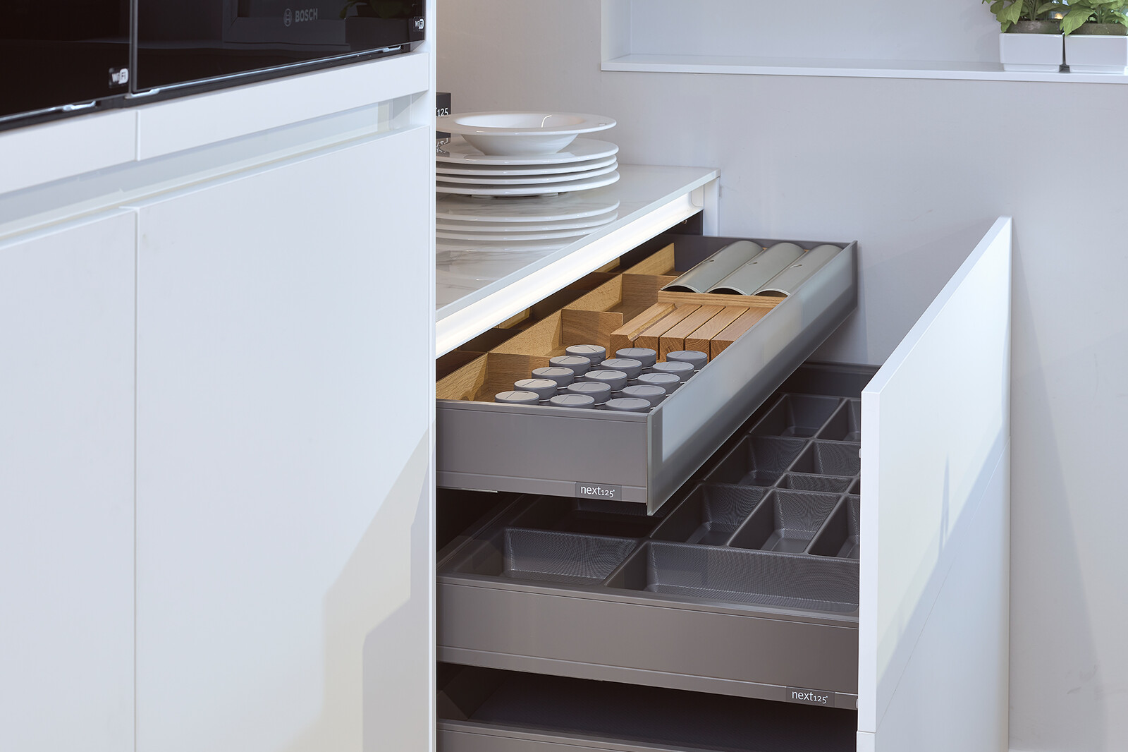 Showroomkeuken next125 - Witte eilandkeuken in fenix met notenhout en luxe lade inrichting